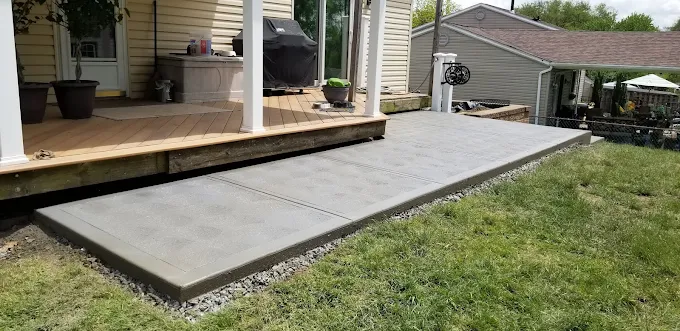Finished custom concrete patio poured alongside a deck in Irwin, PA